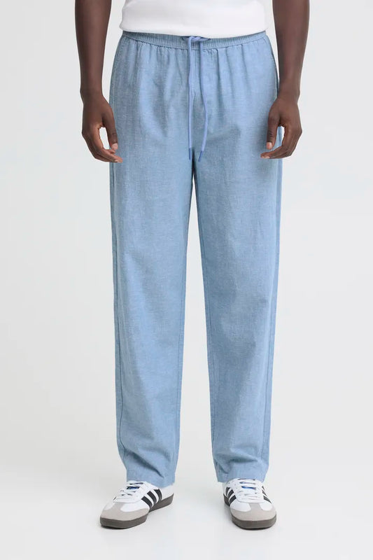 Men's relaxed Trousers Blend Aban Linen Trousers Lichen Blue Relaxed Wear Colour: Dusty Olive Material: 70% Cotton & 30% Linen Person wearing light blue pants and white sneakers on a white background