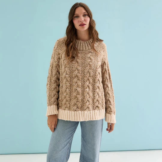 Cara & The Sky Jennie Cable High Neck Balloon Sleeve Jumper Beige Womens Jumper warm baggy jumper Woman wearing a beige cable knit sweater against a light blue background
