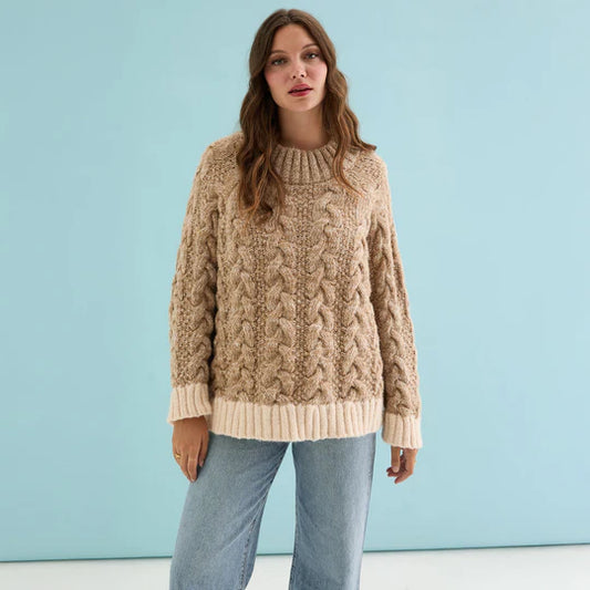 Cara & The Sky Jennie Cable High Neck Balloon Sleeve Jumper Beige Womens Jumper warm baggy jumper Woman wearing a beige cable knit sweater against a light blue background