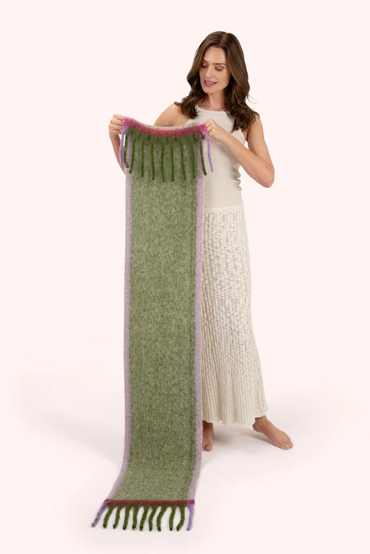 Powder Aria Cosy Scarf Sage Powder accessories womens scarf Woman holding a long green scarf with purple accents on a white background