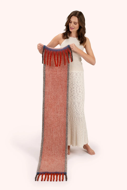 Powder Aria Cosy Scarf Tangerine Powder accessories womens scarf 
Woman holding a long, patterned scarf on a white background