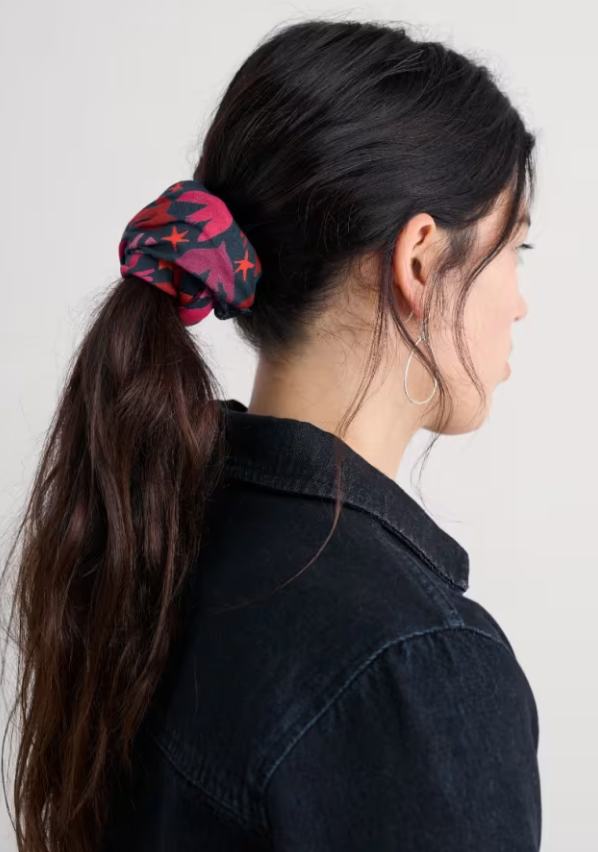 Person with a colorful scrunchie in their hair against a plain background