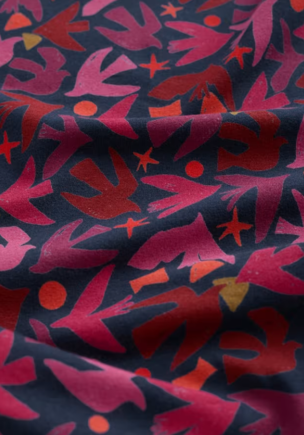 Fabric with abstract pattern of red and pink shapes on a dark blue background