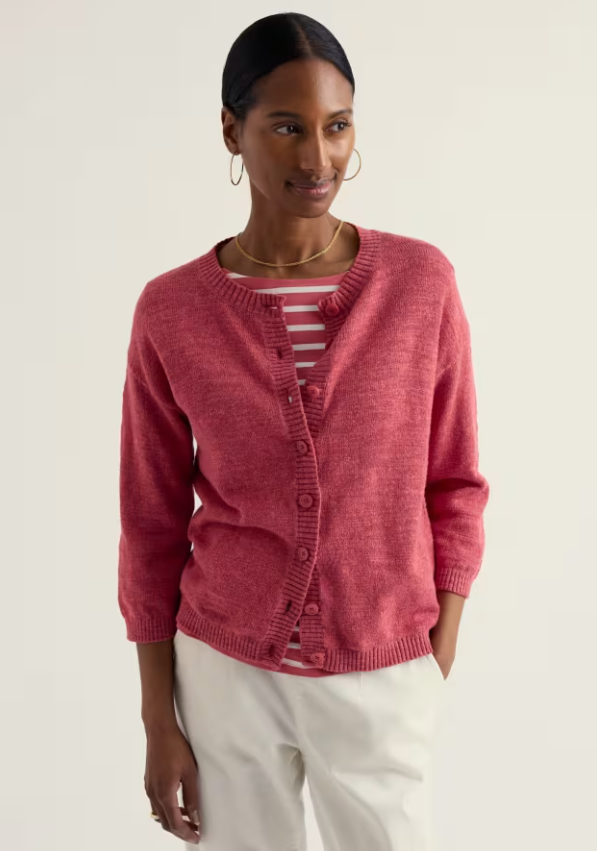 Seasalt Pentire Steps Linen & Organic Cotton Cardigan Echinacea womens Easy fit with a Round neck and Button fastening that's Hand Wash In Cold Water Colour: Echinacea Material: 80% Organic Cotton & 20% Linen Woman wearing a pink cardigan over a striped shirt on a plain background