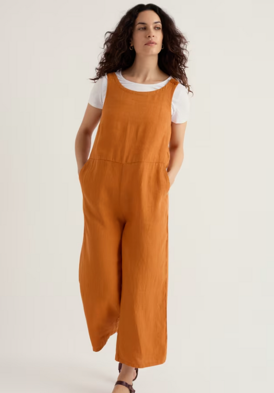 Seasalt Salt Air Wide Leg Jumpsuit Amber womens Neat fit with Wide leg and a Round neck with Angled pockets. Material: 100% Linen Summer style meets comfort in this Seasalt Salt Air wide-leg linen jumpsuit. Woman wearing a mustard yellow overalls with a white shirt underneath on a plain background