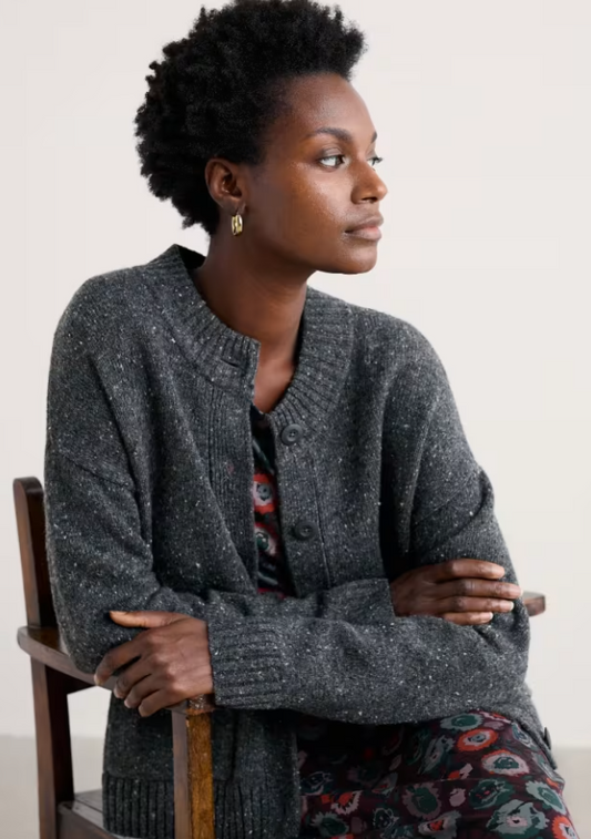 Seasalt Harbour Sands Chunky Crew Neck Cardigan Coal Seasalt clothing womens warm cardigan Woman wearing a gray cardigan sitting on a chair against a plain background