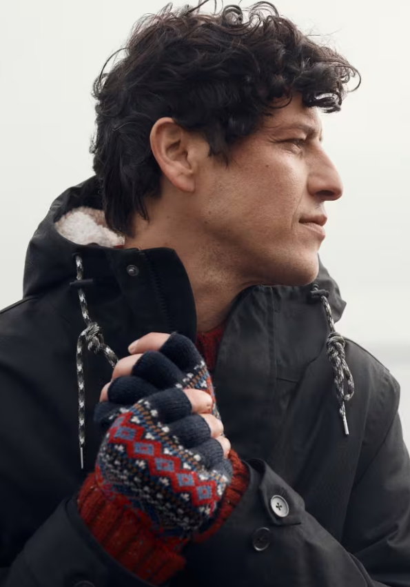 Seasalt Men's Gunvor Fair Isle Fingerless Gloves Sparnon Multi Mens Gloves Seasalt clothing Man wearing a black coat and patterned gloves against a neutral background