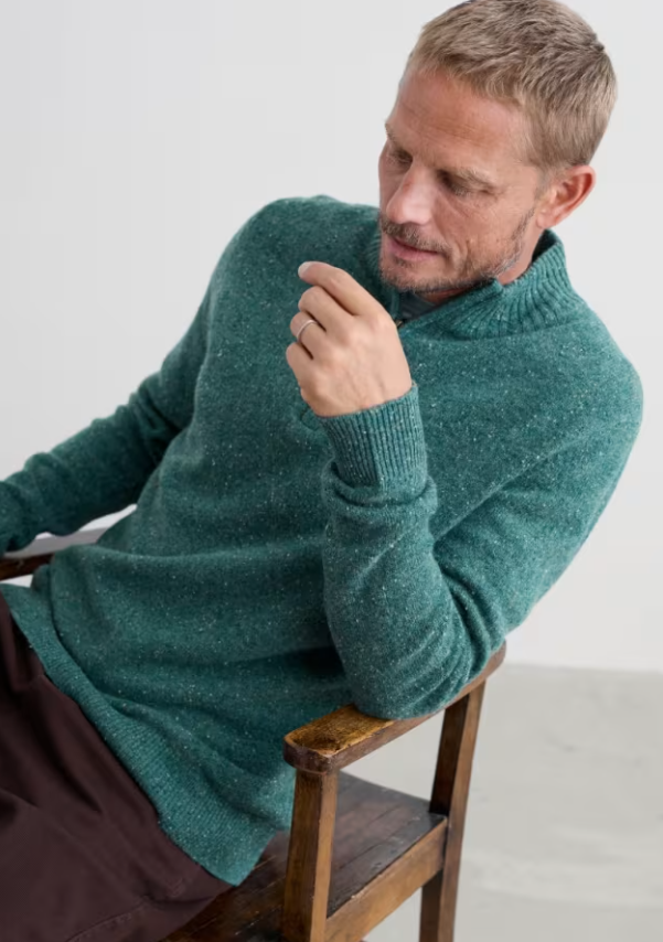 Seasalt Men's Reefpoint Half Zip Jumper Dark Lake Mens Jumper warm jumper zip top Man wearing a teal sweater sitting on a wooden chair against a white background