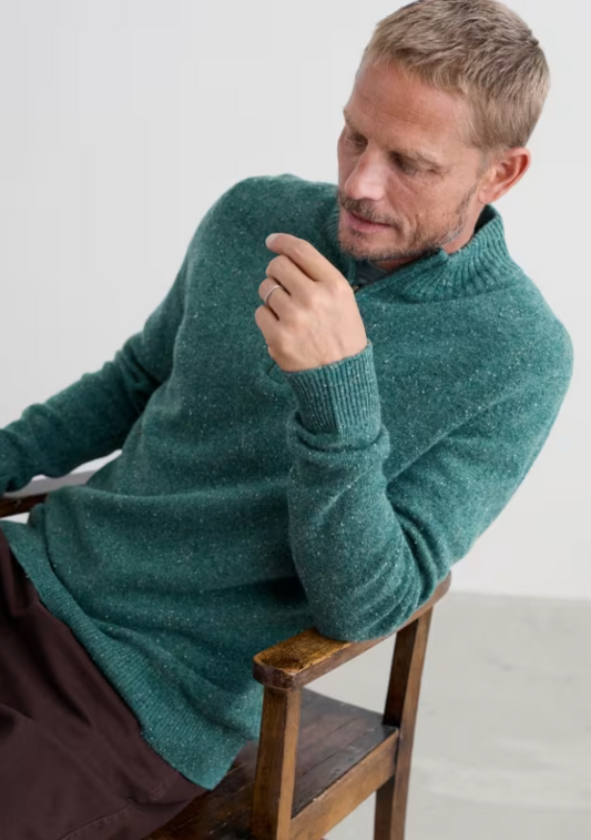 Seasalt Men's Reefpoint Half Zip Jumper Dark Lake Mens Jumper warm jumper zip top Man wearing a teal sweater sitting on a wooden chair against a white background