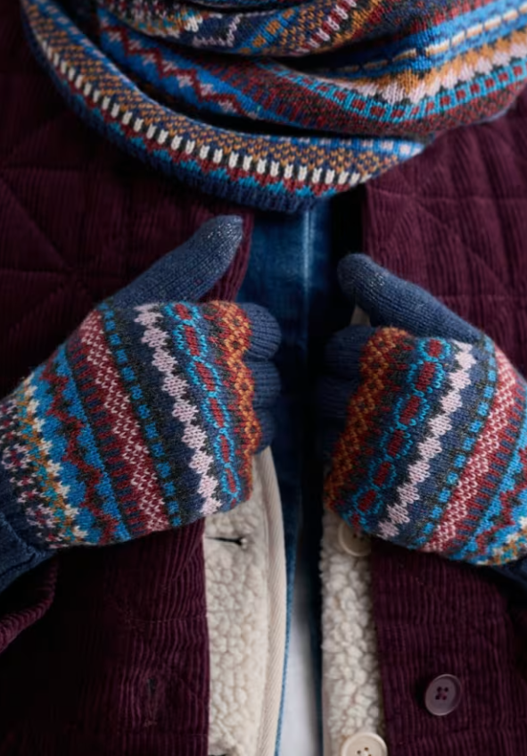Seasalt Very Clever Gloves Star Jasmine Coal Jetty Mix womens gloves Seasalt Clothing Close-up of hands wearing patterned mittens and a scarf, with a focus on texture and color.