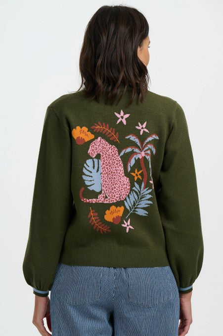 Person wearing a green sweater with a colorful animal design on the back against a white background