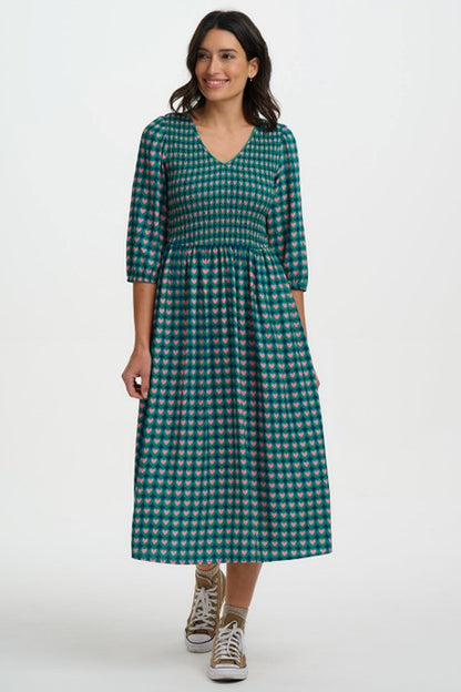 Sugarhill Brighton Della Shirred Midi Dress Navy Heart Tile womens Midi length with Pockets that's Machine Washable (Delicate) Colour: Navy Heart Tile Material: 100% Viscose Description: The Della Shirred Midi Dress Woman wearing a green checkered dress on a white background