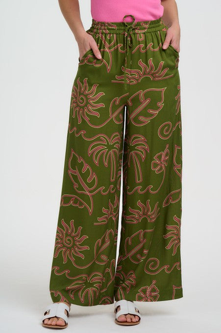 Sugarhill Clothing Brighton Trinny Wide Leg Trousers Khaki Tropical Line Drawing. Womens trouser with Pockets, Full length, Elasticated waistband and is Machine washable (delicate) Material: 100% Lenzing Ecovero Viscose Description: Sugarhill Brighton's Trinny Wide Leg Trousers combine relaxed tailoring with artistic flair. Green patterned pants worn by a person on a white background