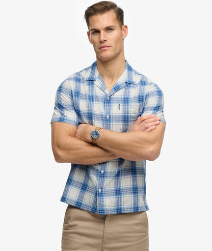 Superdry Cabana Check Short Sleeve Shirt Harbour Check White mens checked shirt. Relaxed fit with Single collar with button fastening and Chest pocket with a signature tab Colour: Harbour Check White Material: 100% Organic Cotton Man wearing a blue and white plaid shirt with arms crossed on a white background