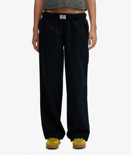 Superdry Cotton Linen Elastic Trousers Eclipse Navy womens Straight Fit with Elasticated drawstring waist and Three pocket design that Embroidered logo on the back pocket Colour: Eclipse Navy Material: 100% Organic Cotton Person wearing black sweatpants on a white background