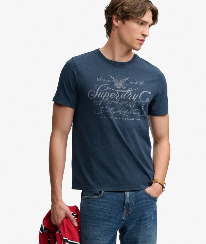 Superdry Mercantile Men's T-Shirt Eclipse Navy. Wit a Relaxed fit Ribbed crew neckline and short sleeves with Distressed trims and Printed graphic across chest Material: 100% Organic Cotton Style Code: M1012434A Colour Code: 98T