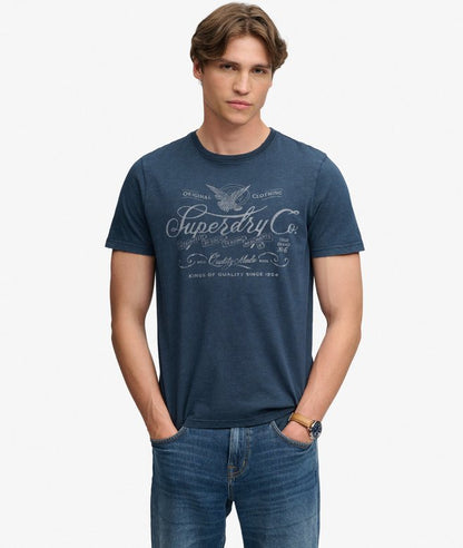 Superdry Mercantile Men's T-Shirt Eclipse Navy. Wit a Relaxed fit Ribbed crew neckline and short sleeves with Distressed trims and Printed graphic across chest Material: 100% Organic Cotton Style Code: M1012434A Colour Code: 98T