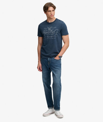 Superdry Mercantile Men's T-Shirt Eclipse Navy. Wit a Relaxed fit Ribbed crew neckline and short sleeves with Distressed trims and Printed graphic across chest Material: 100% Organic Cotton Style Code: M1012434A Colour Code: 98T