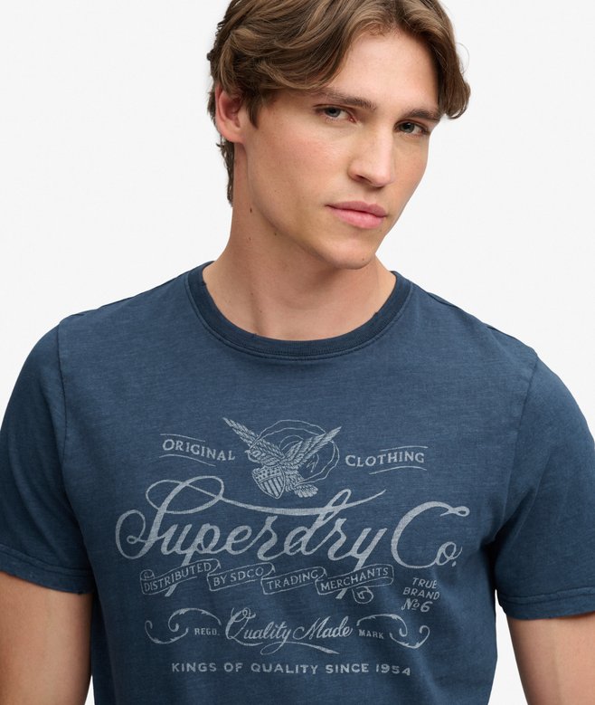 Superdry Mercantile Men's T-Shirt Eclipse Navy. Wit a Relaxed fit Ribbed crew neckline and short sleeves with Distressed trims and Printed graphic across chest Material: 100% Organic Cotton Style Code: M1012434A Colour Code: 98T