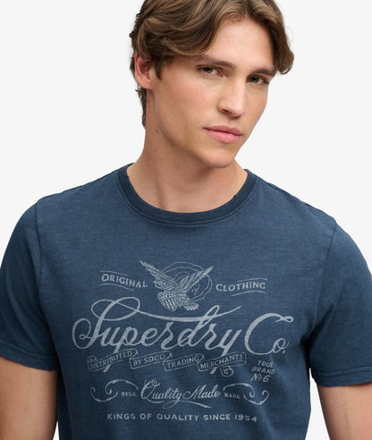 Superdry Mercantile Men's T-Shirt Eclipse Navy. Wit a Relaxed fit Ribbed crew neckline and short sleeves with Distressed trims and Printed graphic across chest Material: 100% Organic Cotton Style Code: M1012434A Colour Code: 98T