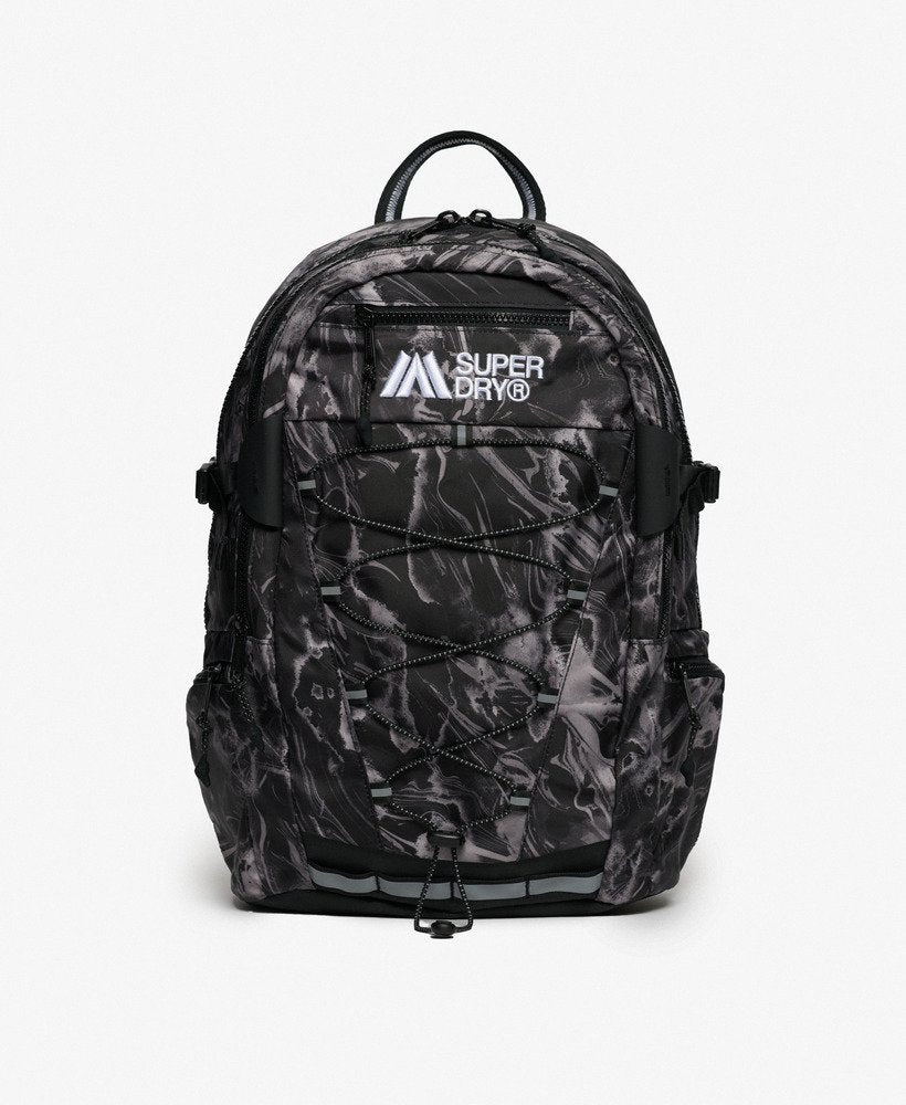 Superdry Outdoor 28L Backpack Woodgrain Print Black featuring Top handle with Main zipped compartment with internal mesh zip pocket and Internal laptop sleeve with hook and loop fastening with Two side pockets and a Padded back panel with Adjustable straps and mbroidered Superdry logo plus Superdry logo badge on strap Colour: Skate Navy Material: Polyester & Nylon Size: H 45.5cm x W 30cm x D 13.5cm