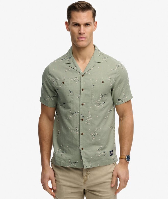 Superdry Short Sleeve Printed Beach Shirt Shibori Blossom Sage mens Relaxed fit Short sleeves with Button fastening and Two button down chest pockets. Colour: Shibori Blossom Sage Material: 100% Organic Cotton Man wearing a green patterned shirt on a white background
