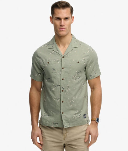 Superdry Short Sleeve Printed Beach Shirt Shibori Blossom Sage mens Relaxed fit Short sleeves with Button fastening and Two button down chest pockets. Colour: Shibori Blossom Sage Material: 100% Organic Cotton Man wearing a green patterned shirt on a white background