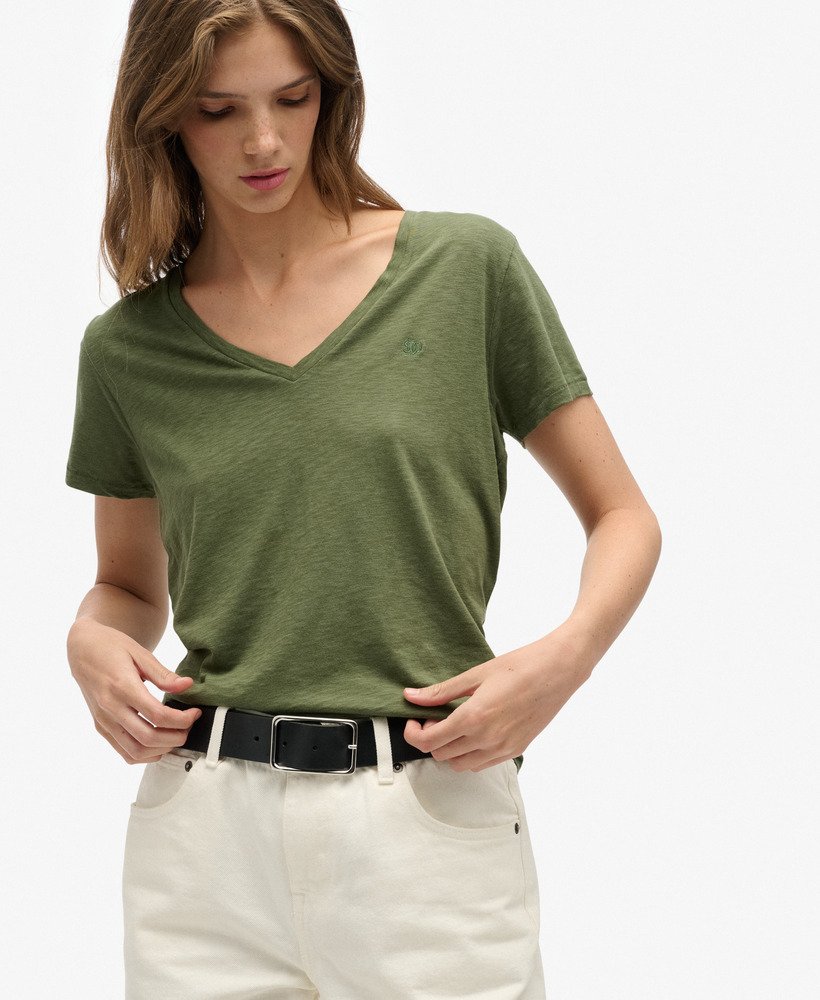 Superdry Studios Slub Embroidered V-Neckline T-Shirt Four Leaf Clover Buy 3 Studio or Slub T-Shirts For £50 womens tee with a Relaxed fit and V-Neckline with short sleeves and Embroidered text on the chest 95% Viscose, Acrylic 4% & 1% Metallic Fibre Woman wearing a green t-shirt and white pants on a plain background