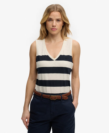 Superdry Studios V-Neckline Vest Top Off White/Navy Wide Stripe womens top that's Relaxed fit with a V-Neckline and Embroidered logo on the chest Colour: Off White/Navy Wide Stripe Material: 60% Cotton & 40% Lyocell Woman wearing a striped tank top and dark pants on a white background