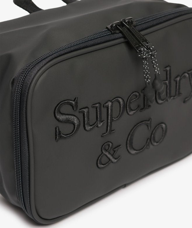 Superdry Travel Wash Bag Black. Wash bag with Top handle and Zip sealed plastic compartment with Internal zip pocket and Mesh fabric laid on pockets Material: 100% Polyester