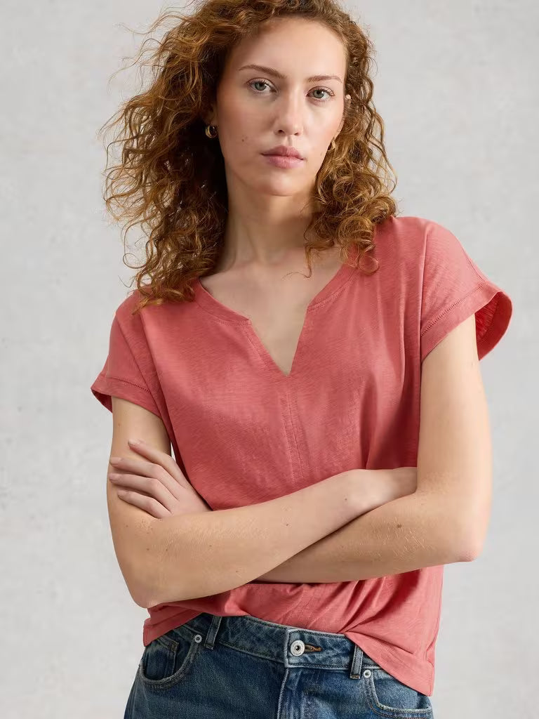White Stuff Nelly Notch Neck Short Sleeve T-shirt Mid Pink womens Buy 2 Selected T-Shirts For £45 Notch Neck with Short Sleeve and a Regular Fit that's Machine Washable Colour: Mid Pink Material: 100% Cotton Style Code: 445349 Woman wearing a pink t-shirt with arms crossed against a light gray background