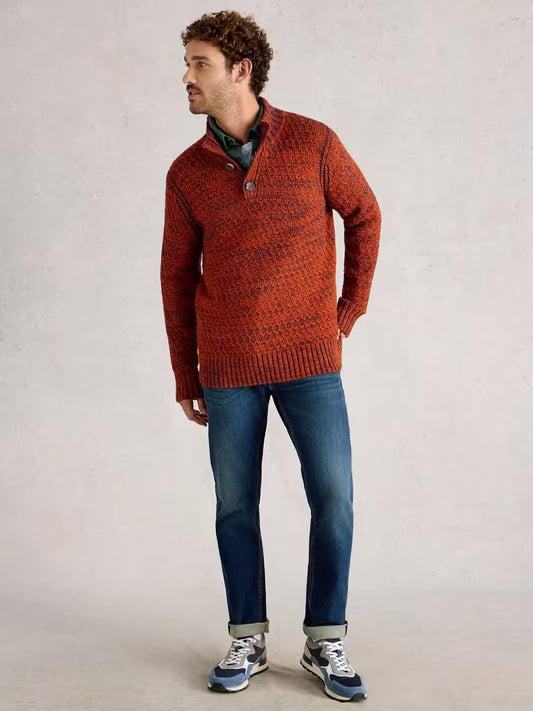 Man wearing a red sweater and blue jeans against a plain background