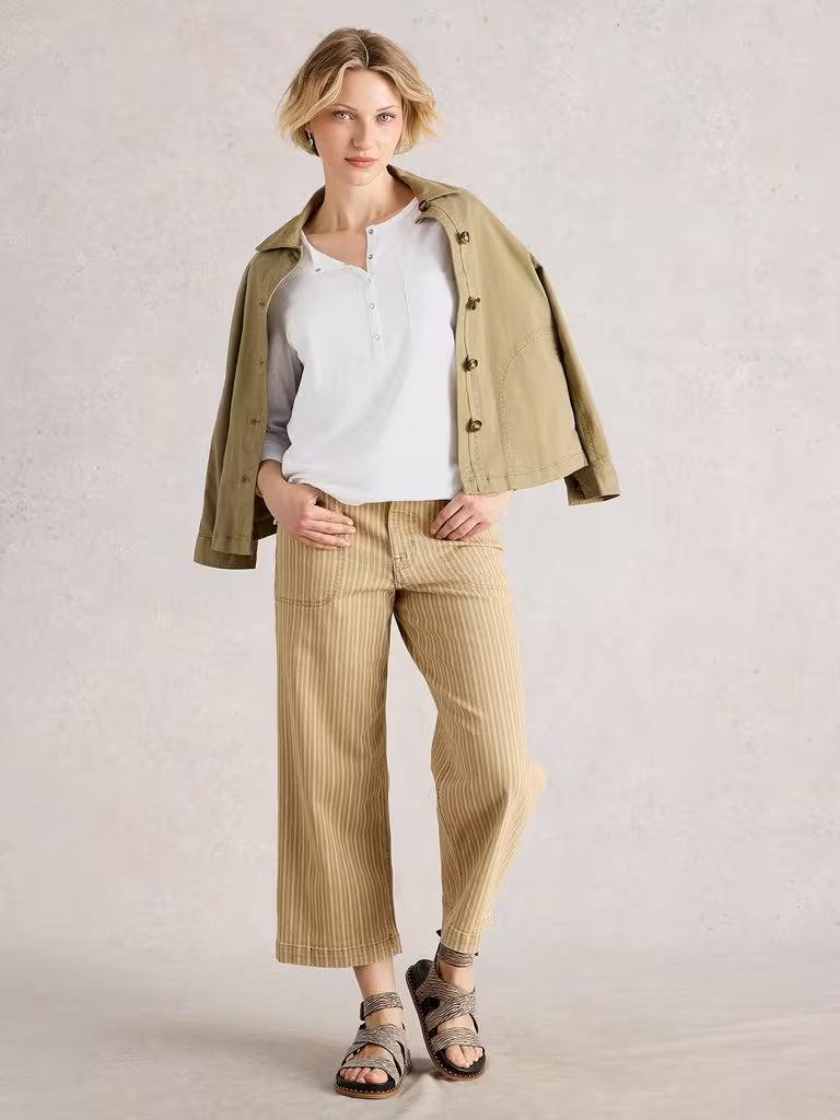 White Stuff Holly Pocket Brilliant White Womens tee White Stuff Clothing Woman wearing a beige jacket, white shirt, and striped pants on a plain background