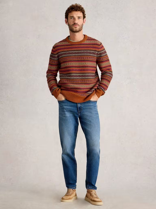 White Stuff Ossett Fairisle Crew Neck Orange Mens Jumper White Stuff Clothing Man wearing a patterned sweater and blue jeans against a plain background